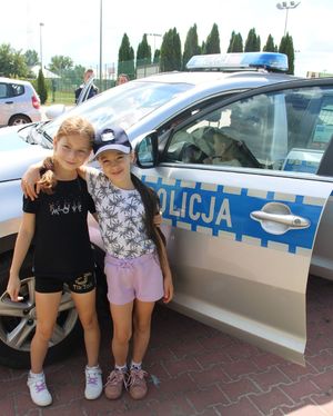 dwie dziewczynki przy oznakowanym radiowozie policyjnym
