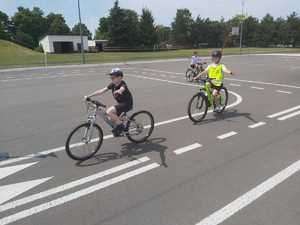 uczniowie na rowerach jadacy uliczkami miasteczka drogowego